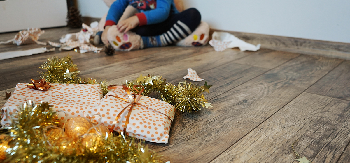 A child sitting near a wrapped Christmas present