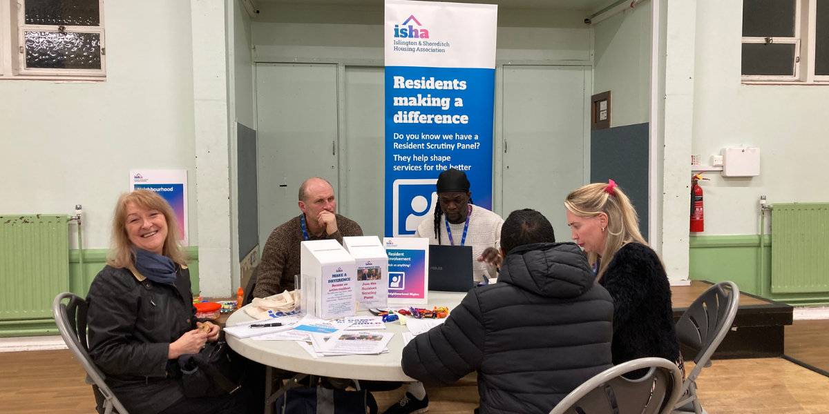 Residents and staff chat around a table.