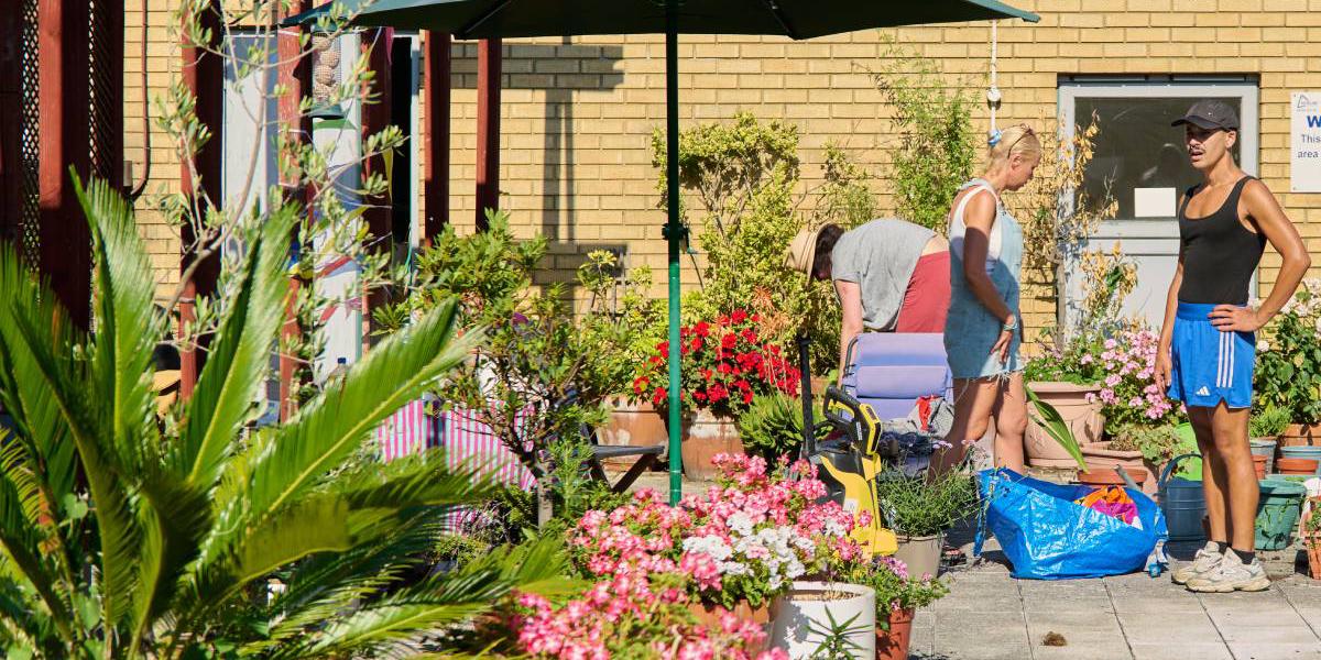 Sophie (Resident Involvement Leader) and a gardener from EcoACTIVE in the courtyard garden at Delta House with potted plants.