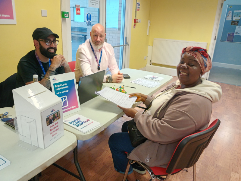 A resident is sitting at a table across from members of our repairs team giving her feedback