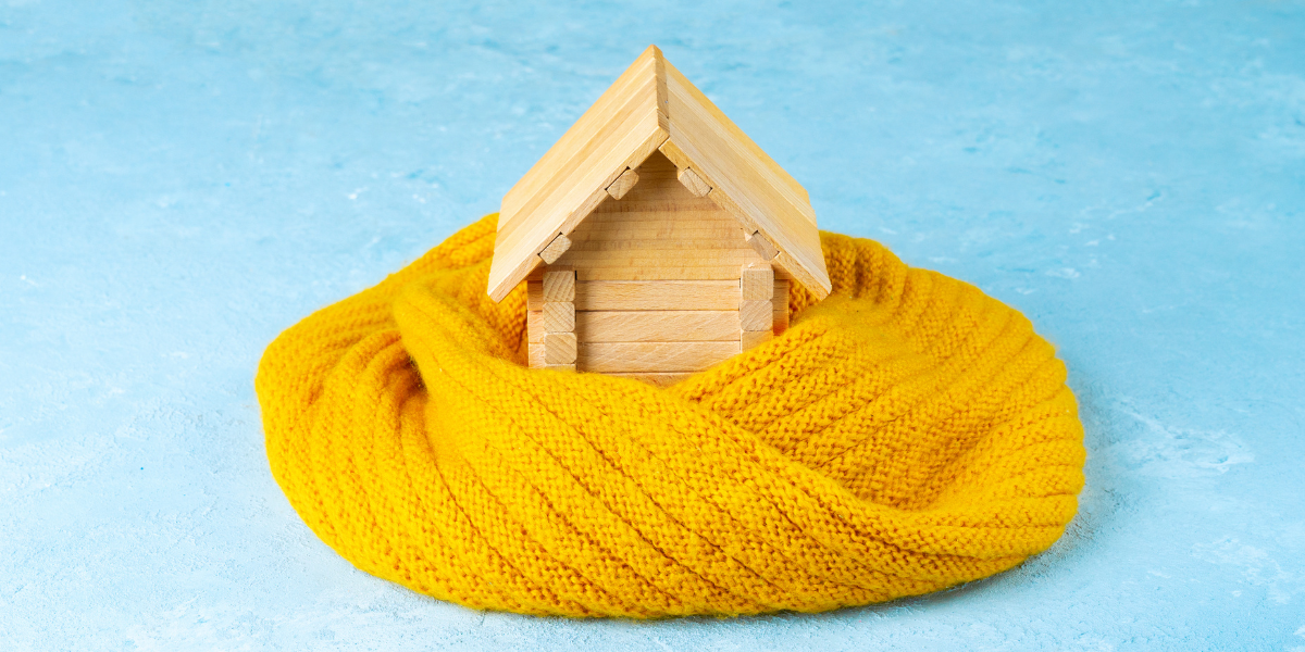 A wooden figure of a house, wrapped in a scarf. 
