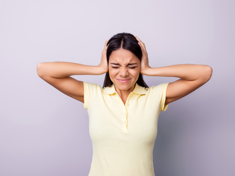 A woman covers hear ears to block out loud noise. 